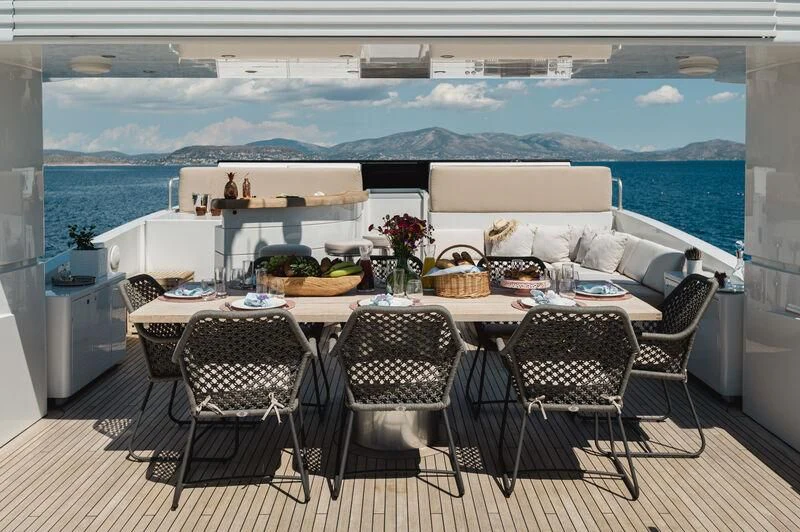 a table with chairs and a large window with a view of the ocean aboard LOANA Yacht for Sale