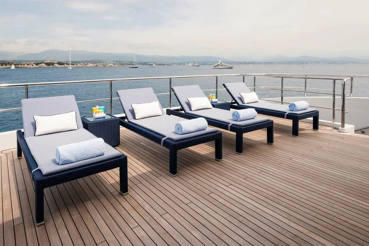 a deck with a table and chairs on it aboard COCKTAILS Yacht for Sale
