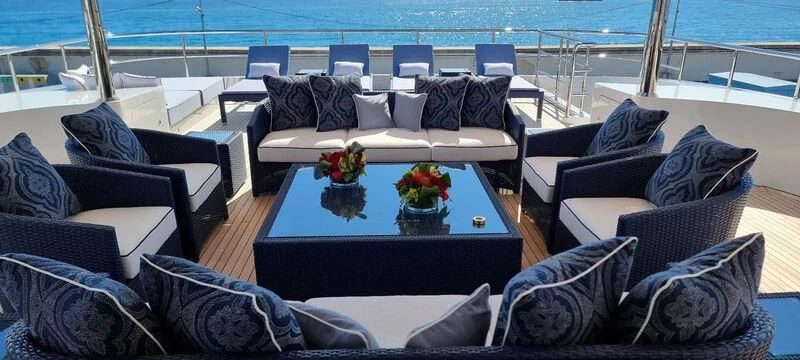 a living room with a blue couch and a table with flowers on it aboard COCKTAILS Yacht for Sale