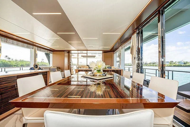 a room with a wood table and chairs and a large window aboard VOYAGER Yacht for Sale