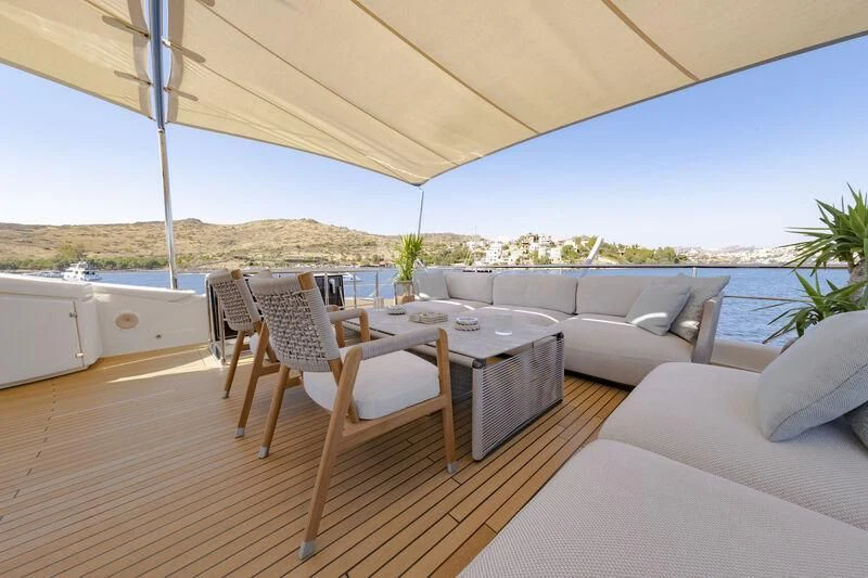 a large open area with a table and chairs and a couch aboard REFLECT Yacht for Sale