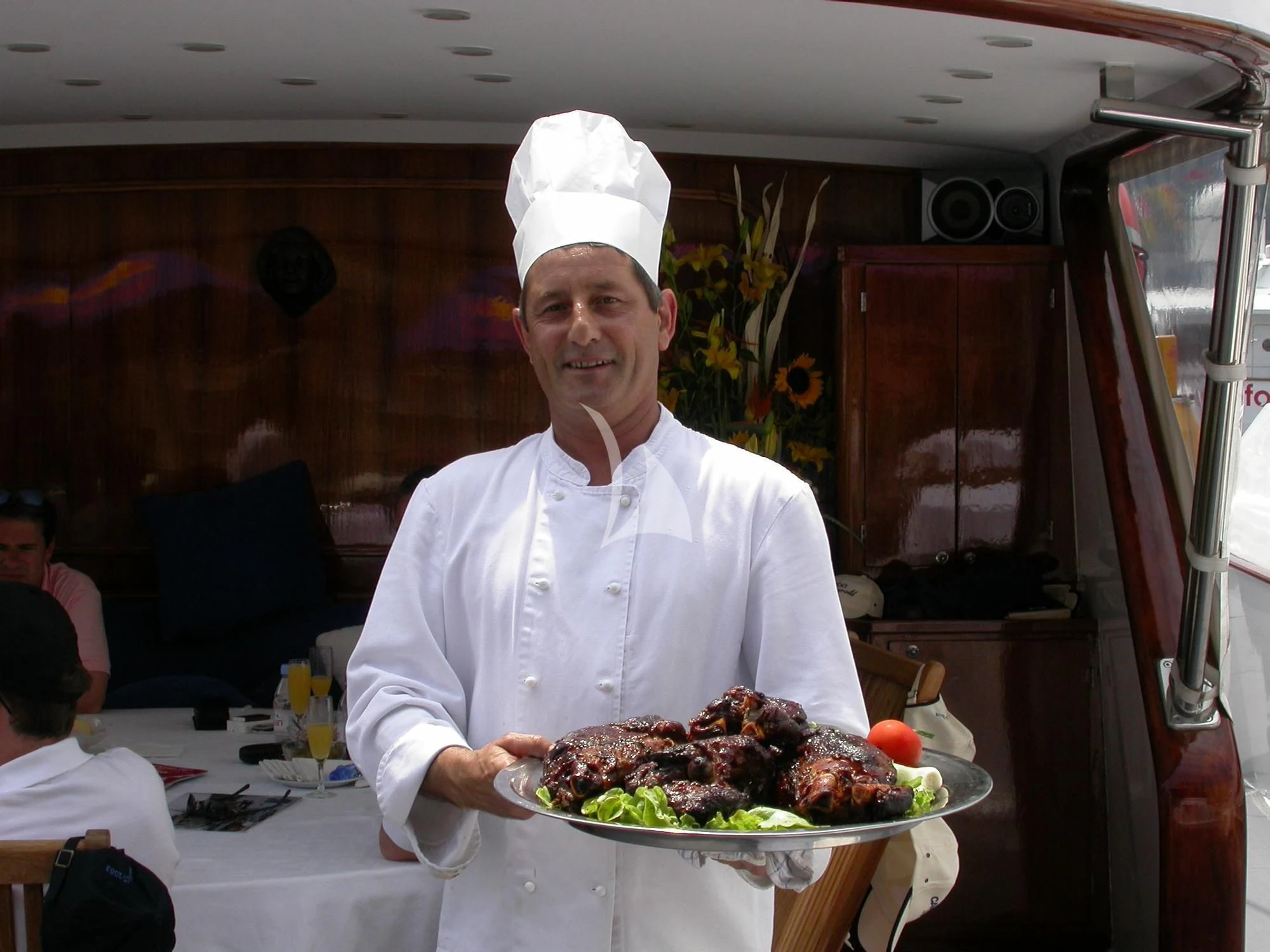 a chef holding a plate of food aboard AVA Yacht for Charter