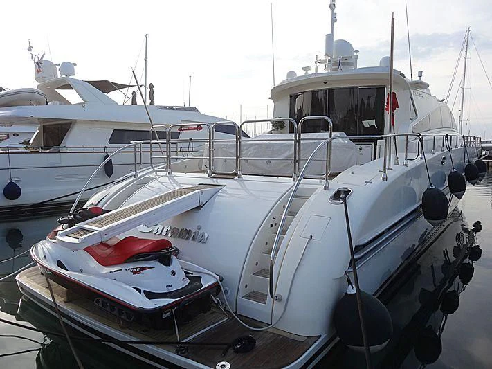 several boats docked at a pier with HMS M33 in the background aboard PALOMA Yacht for Sale
