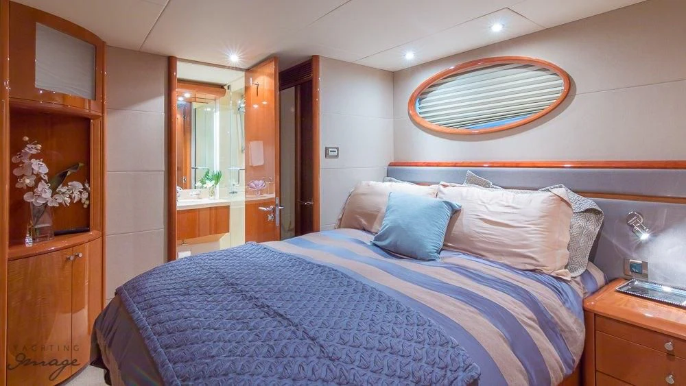 a bed with a blue comforter aboard CHIP Yacht for Sale