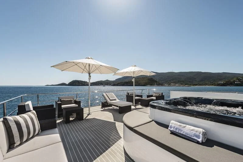 a deck with chairs and umbrellas on it by the water aboard OURWAY Yacht for Sale