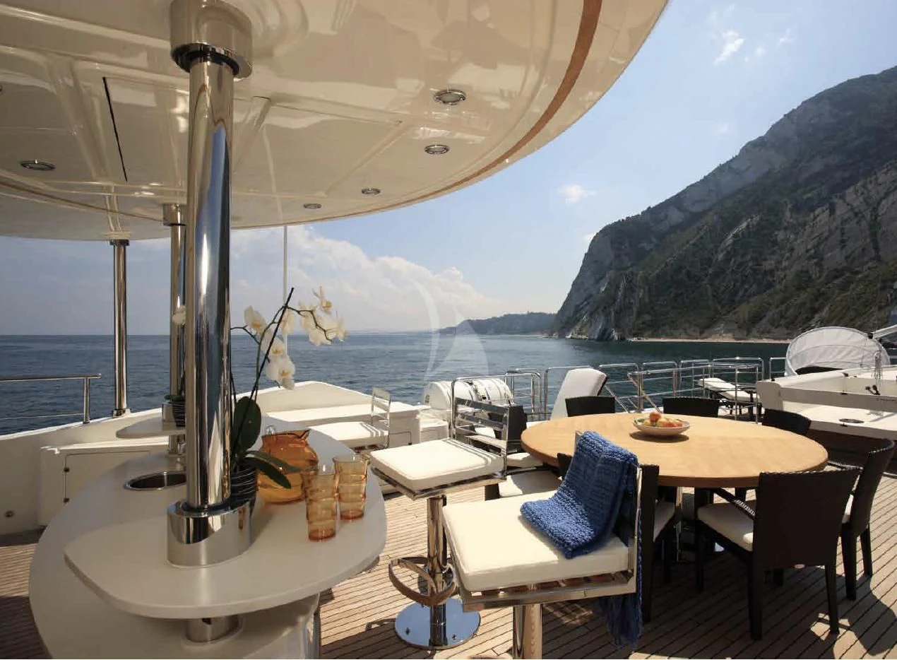 a table with chairs and a large body of water in the background aboard O'LION Yacht for Sale