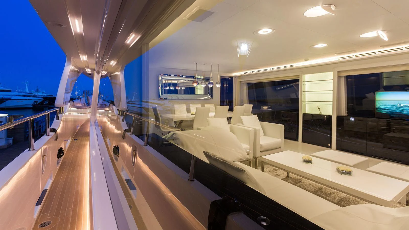 a room with a large window and a large room with chairs and a table and a television aboard GALA Yacht for Sale