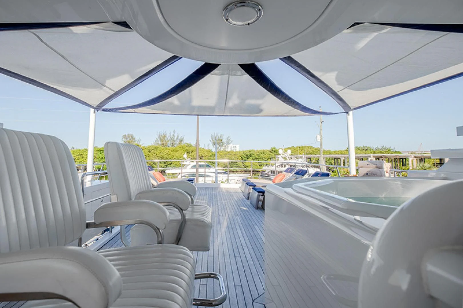 inside of a vehicle with chairs and a large tent with a view of the beach and trees and aboard NEVER ENOUGH Yacht for Charter