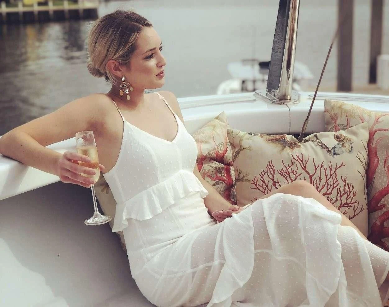 a woman sitting on a couch drinking a glass of water aboard NEVER ENOUGH Yacht for Charter