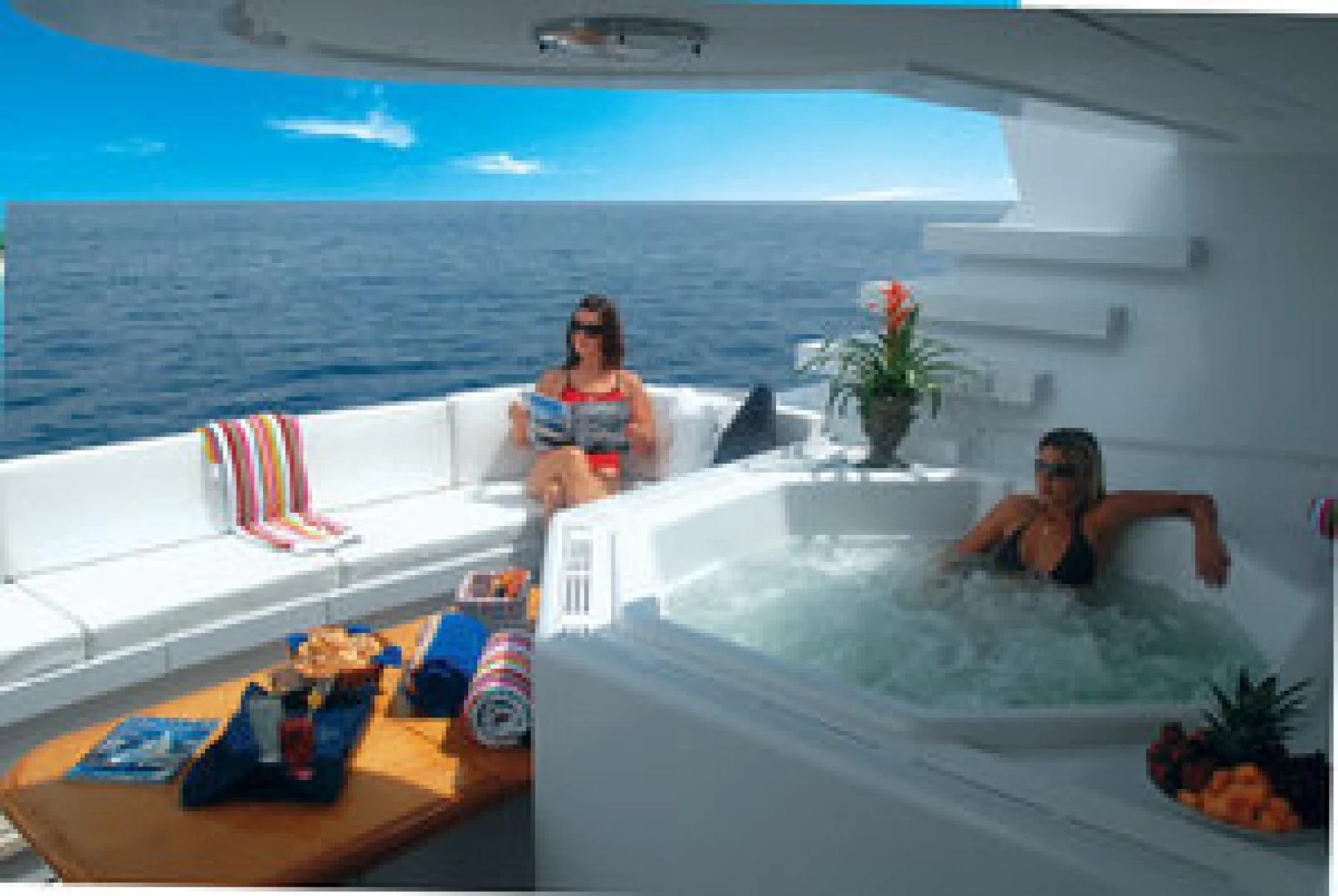 a couple of women sitting on a couch in a room with a large body of water and a aboard NEVER ENOUGH Yacht for Charter