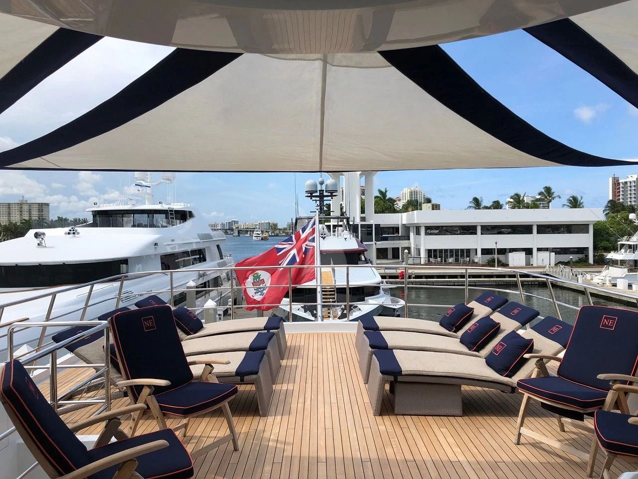 a deck with a deck and chairs and a large ship in the background aboard NEVER ENOUGH Yacht for Charter