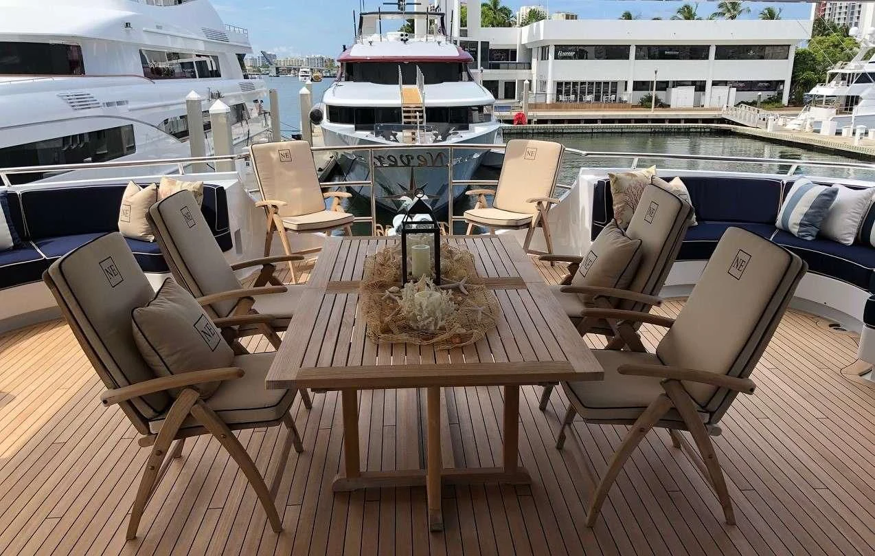 a table with chairs on it next to a boat aboard NEVER ENOUGH Yacht for Charter