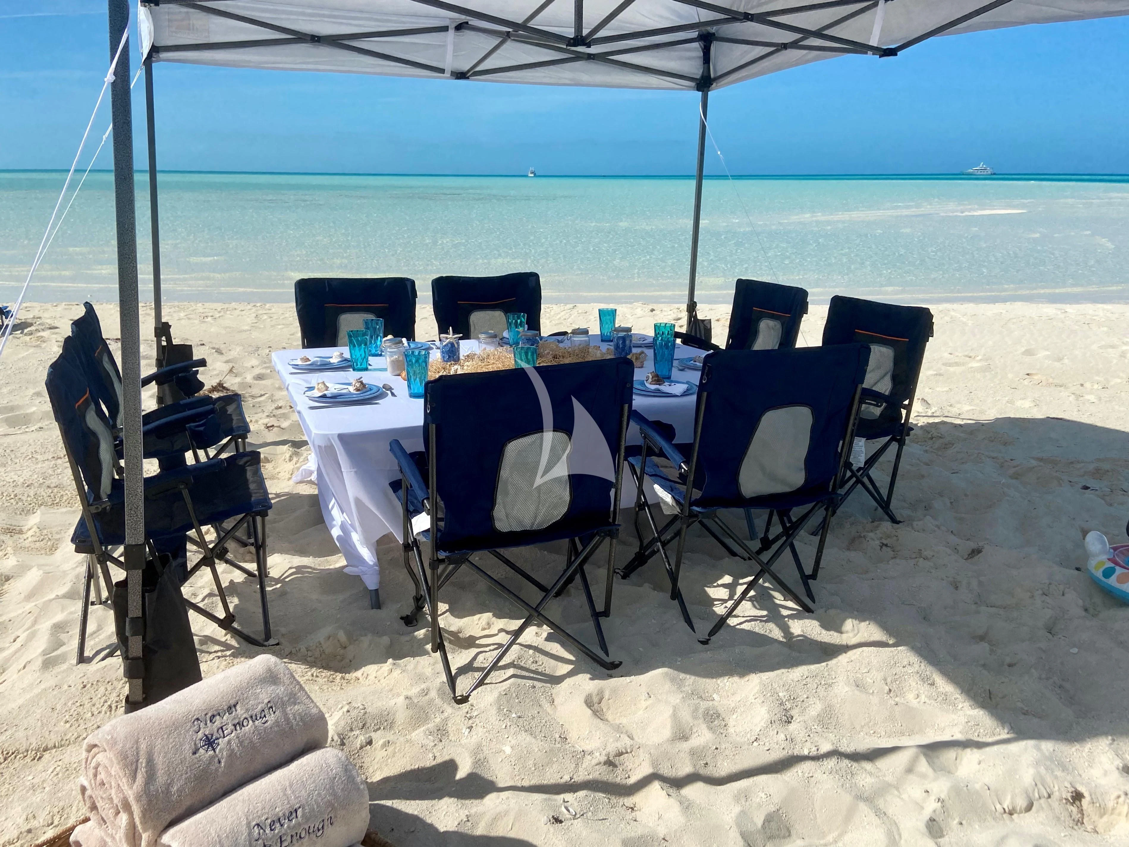 a table set up on the beach aboard NEVER ENOUGH Yacht for Charter