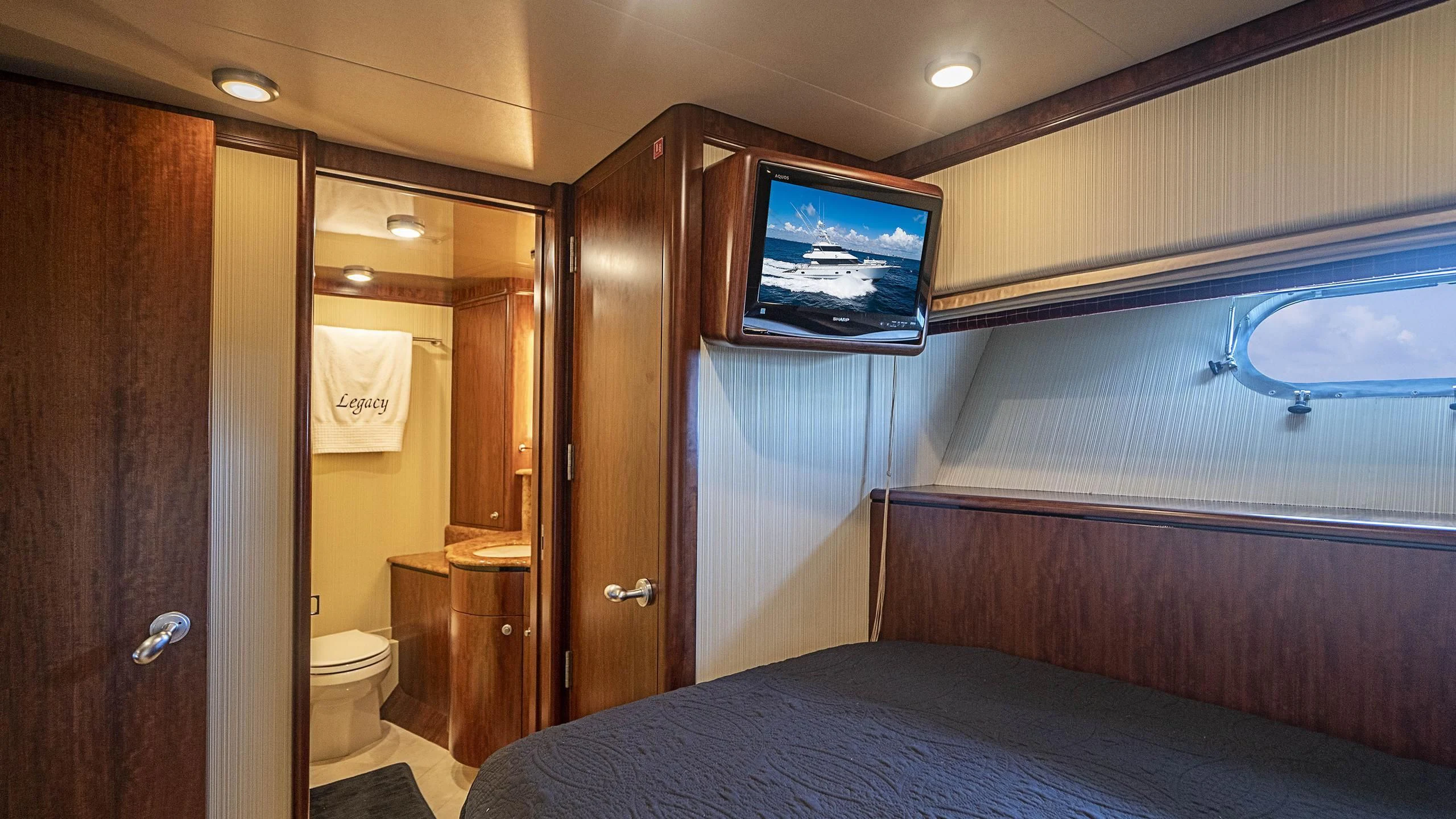 a bedroom with a bed and a television on the wall aboard GRAND LEGACY Yacht for Sale