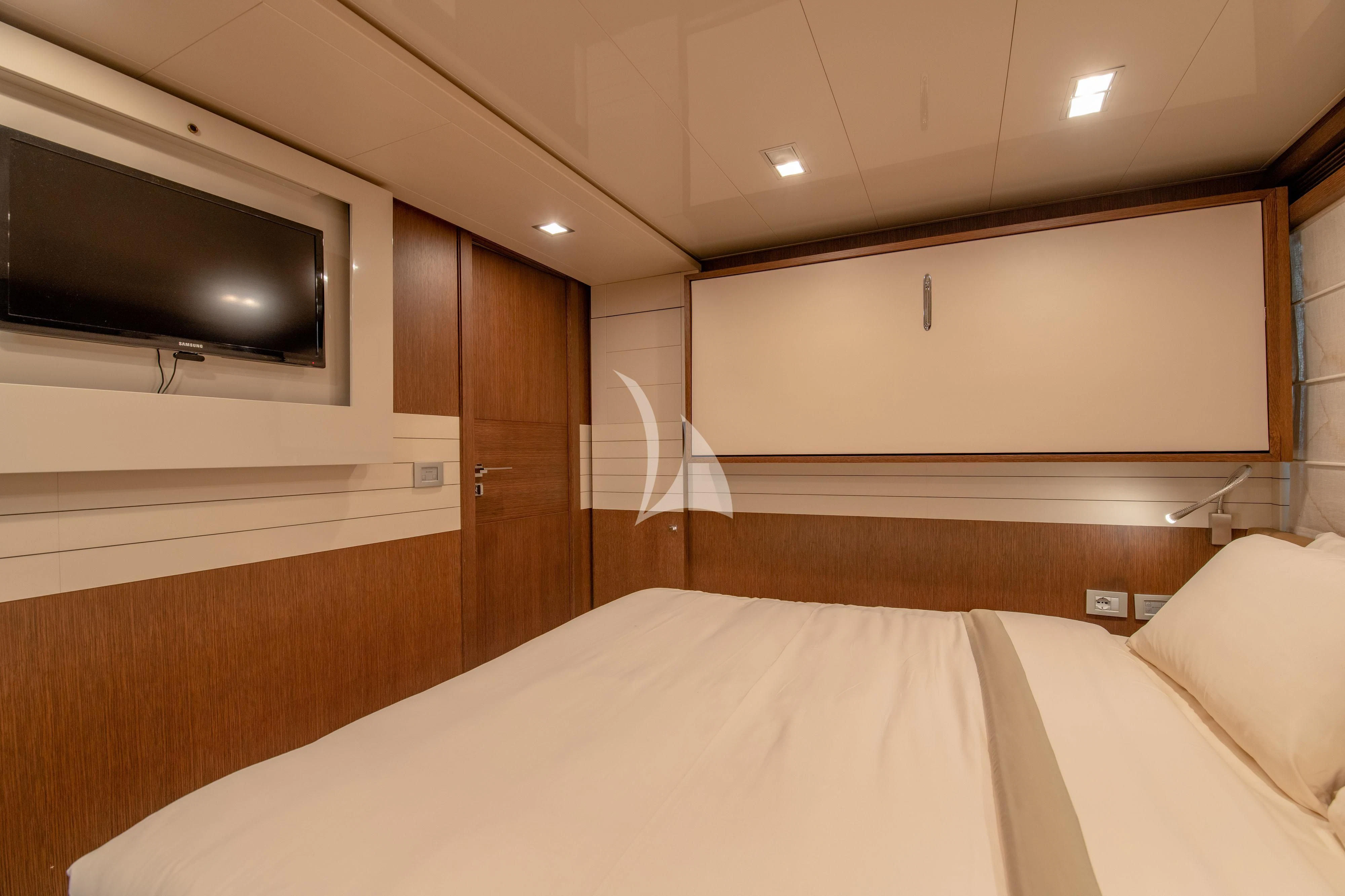 a bed with a television on the wall aboard INFINITAS Yacht for Charter