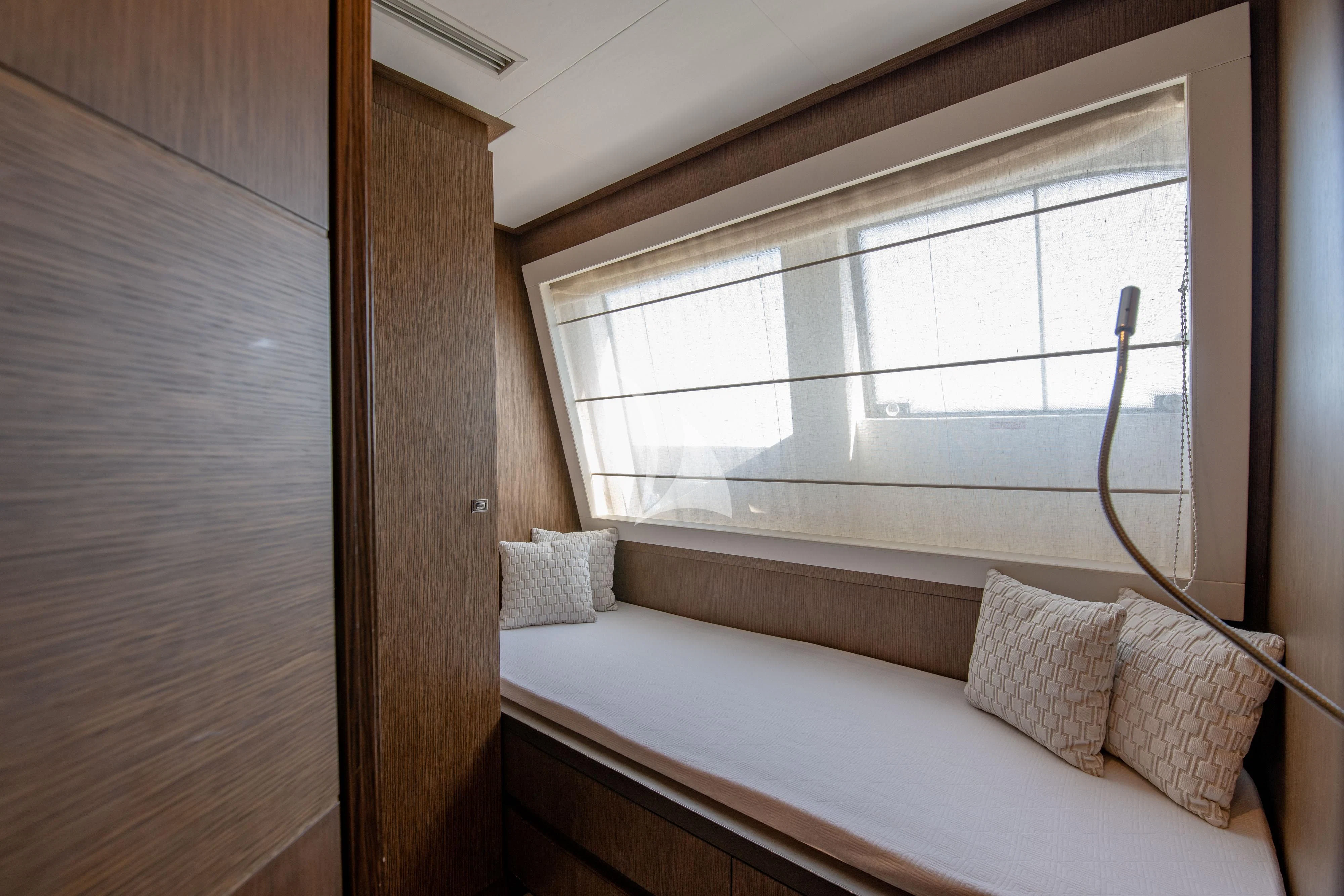 a bed with a white pillow and a wooden wall aboard INFINITAS Yacht for Charter