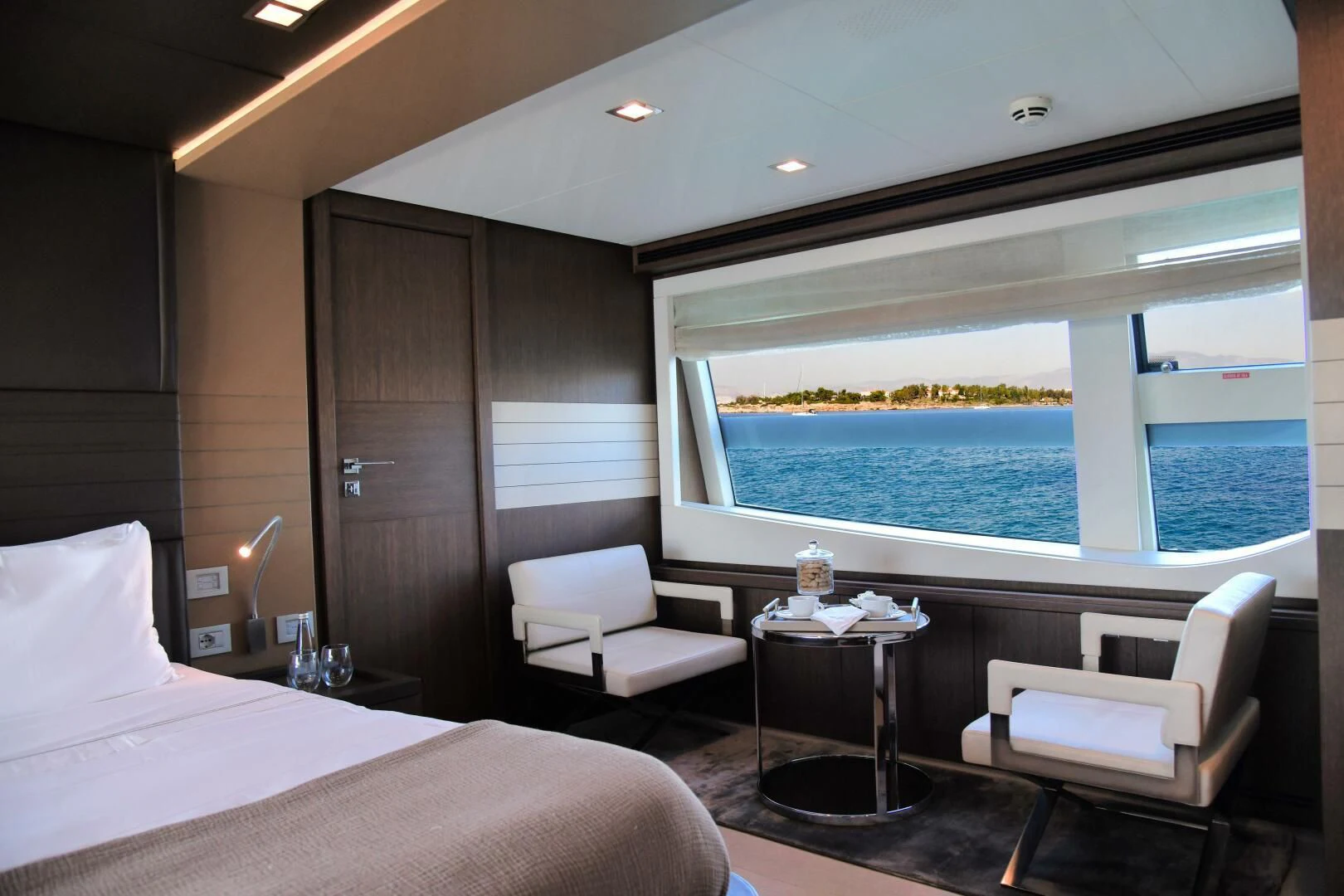 a room with a bed and a table and a chair aboard INFINITAS Yacht for Charter