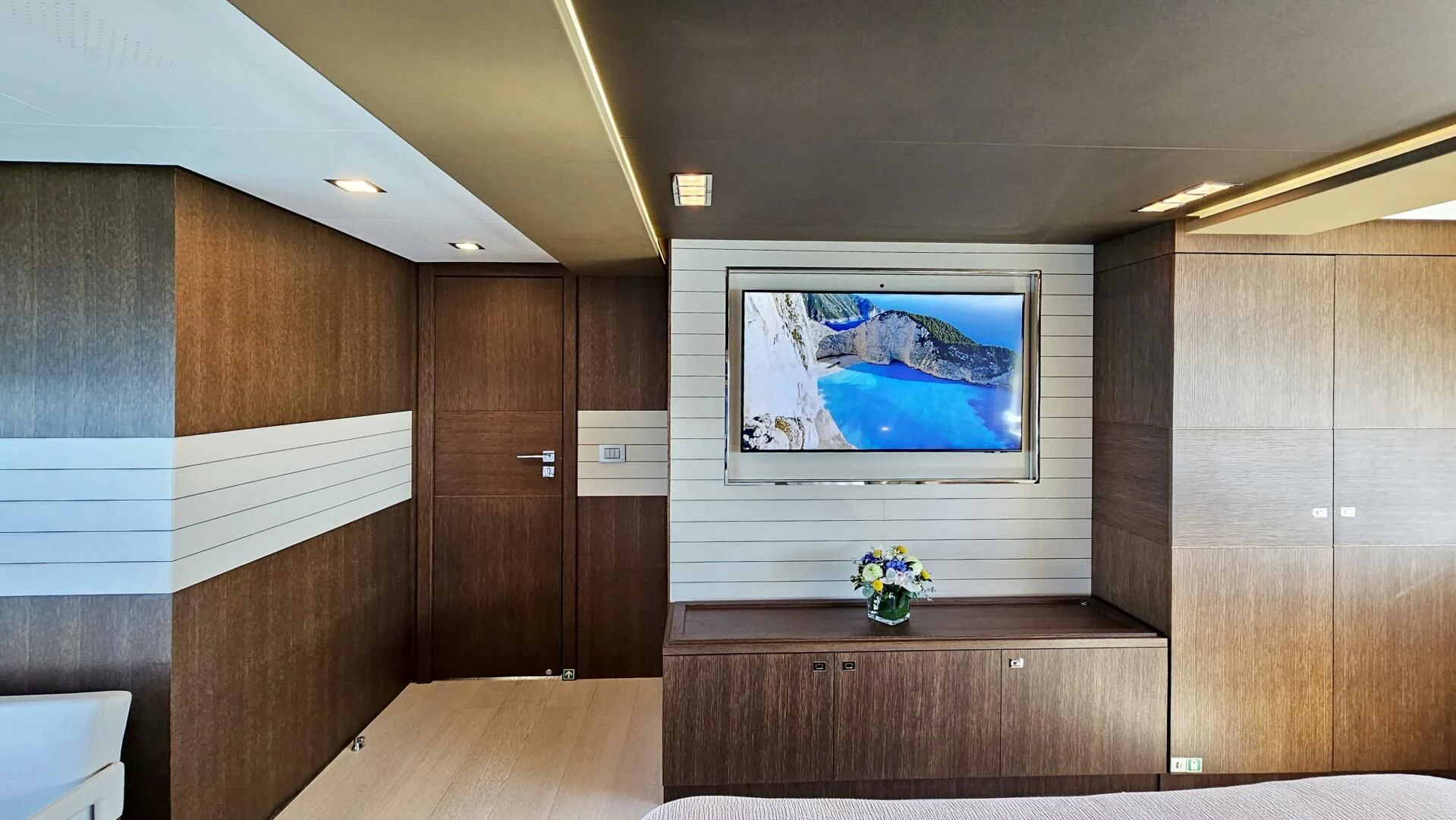 a room with a tv and a wood cabinet aboard INFINITAS Yacht for Charter