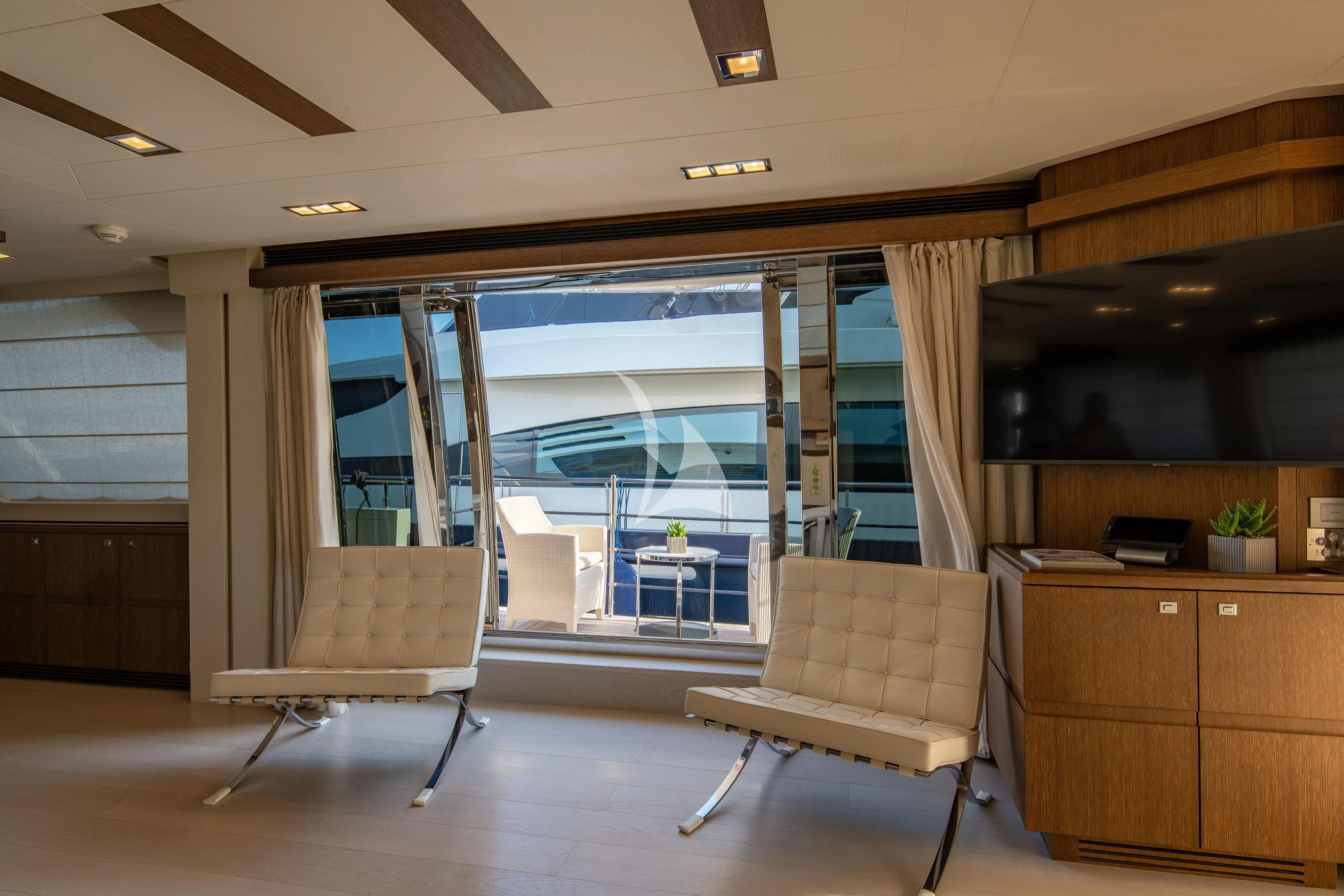 a room with a chair and a table and a tv aboard INFINITAS Yacht for Charter