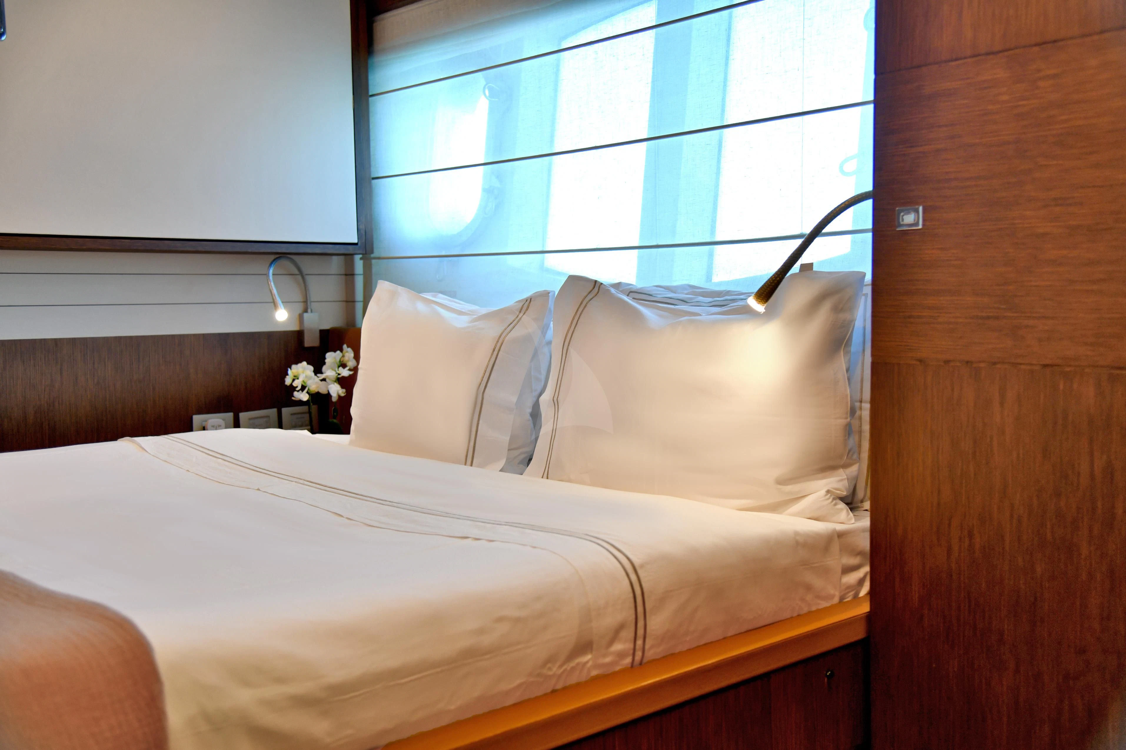 a bed with white sheets and pillows aboard INFINITAS Yacht for Charter