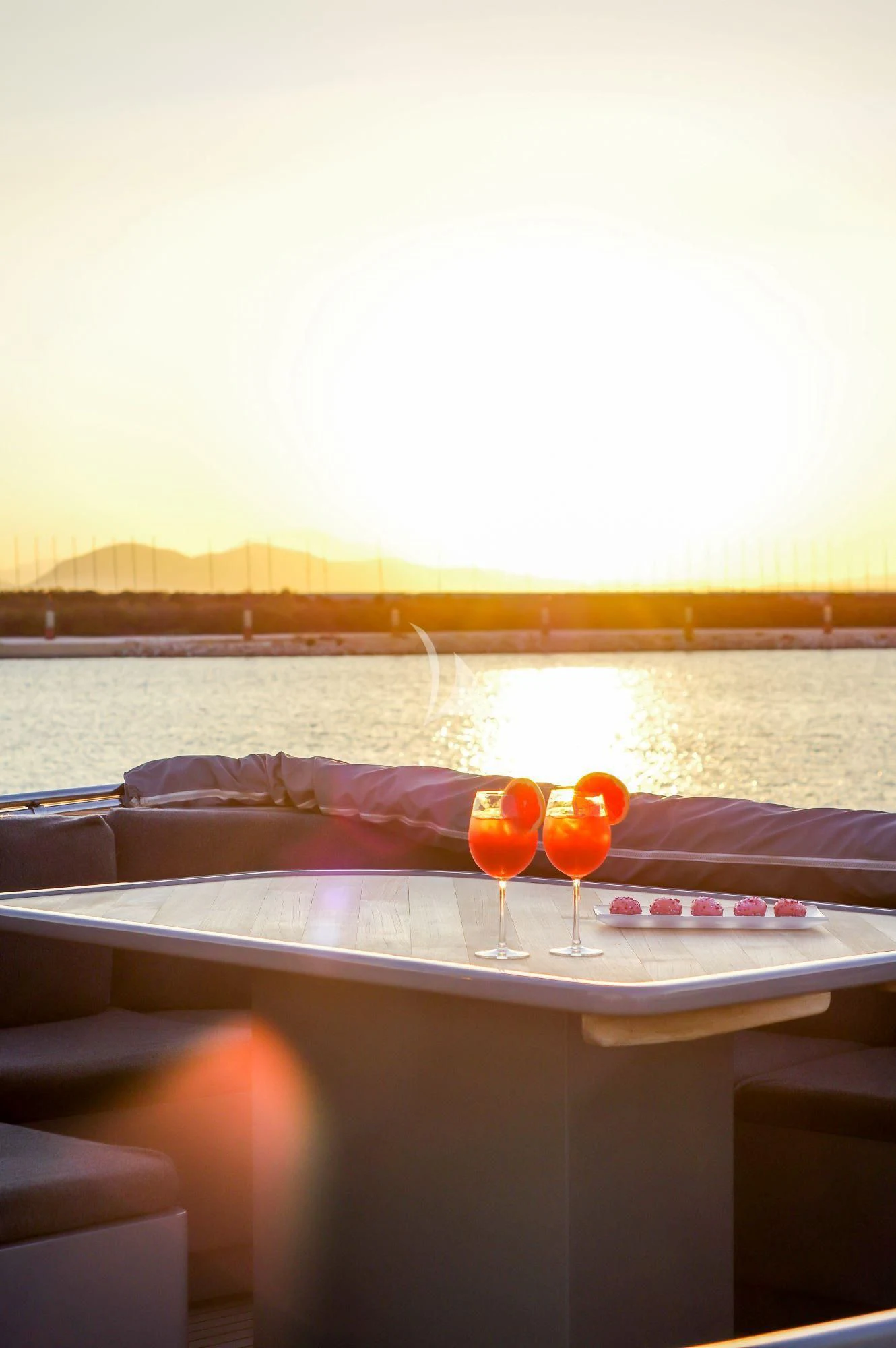 a table with glasses of wine and a view of a city aboard SATORI Yacht for Sale