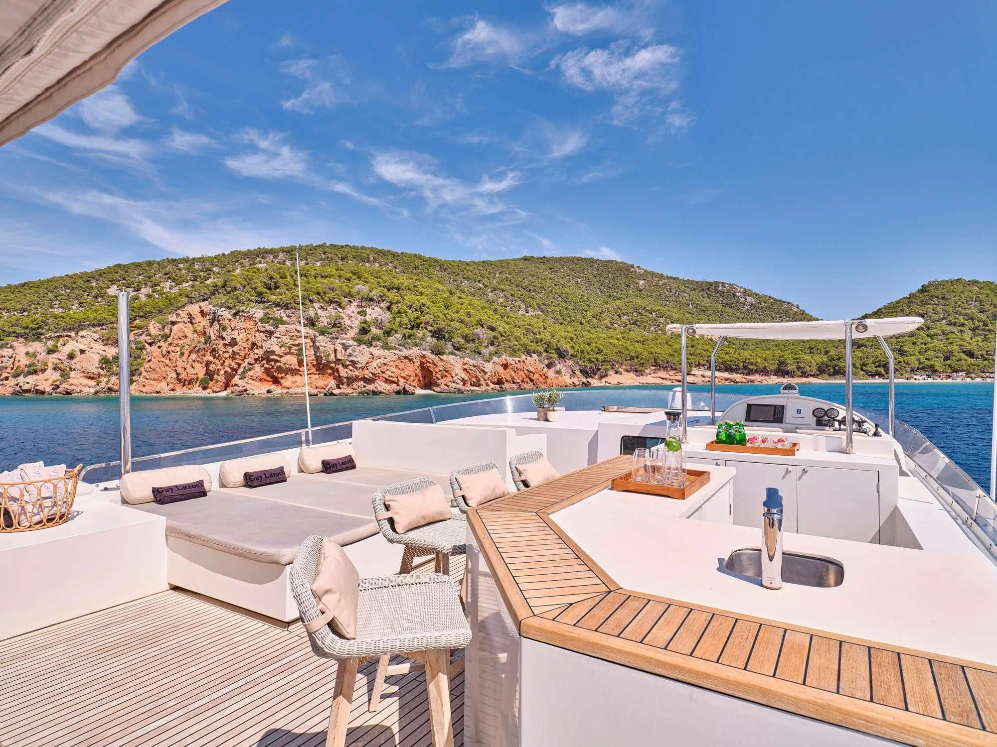a deck with chairs and a table on it by a body of water aboard SANJANA Yacht for Sale