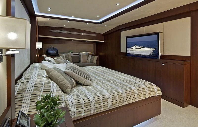 a bed with a television on the wall aboard SANJANA Yacht for Sale
