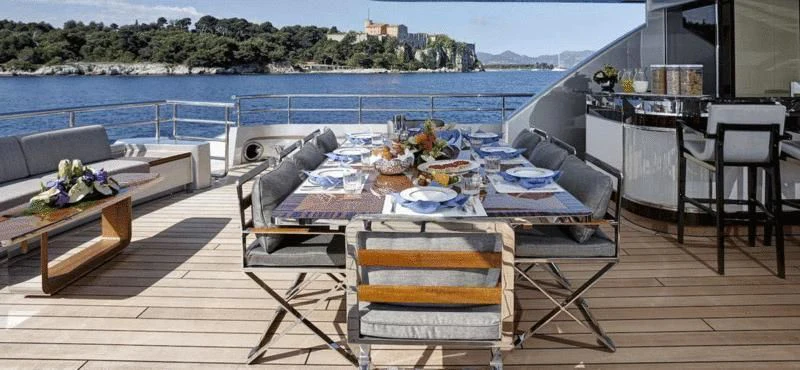 a deck with a table and chairs on it aboard EXCELLENCE V Yacht for Sale