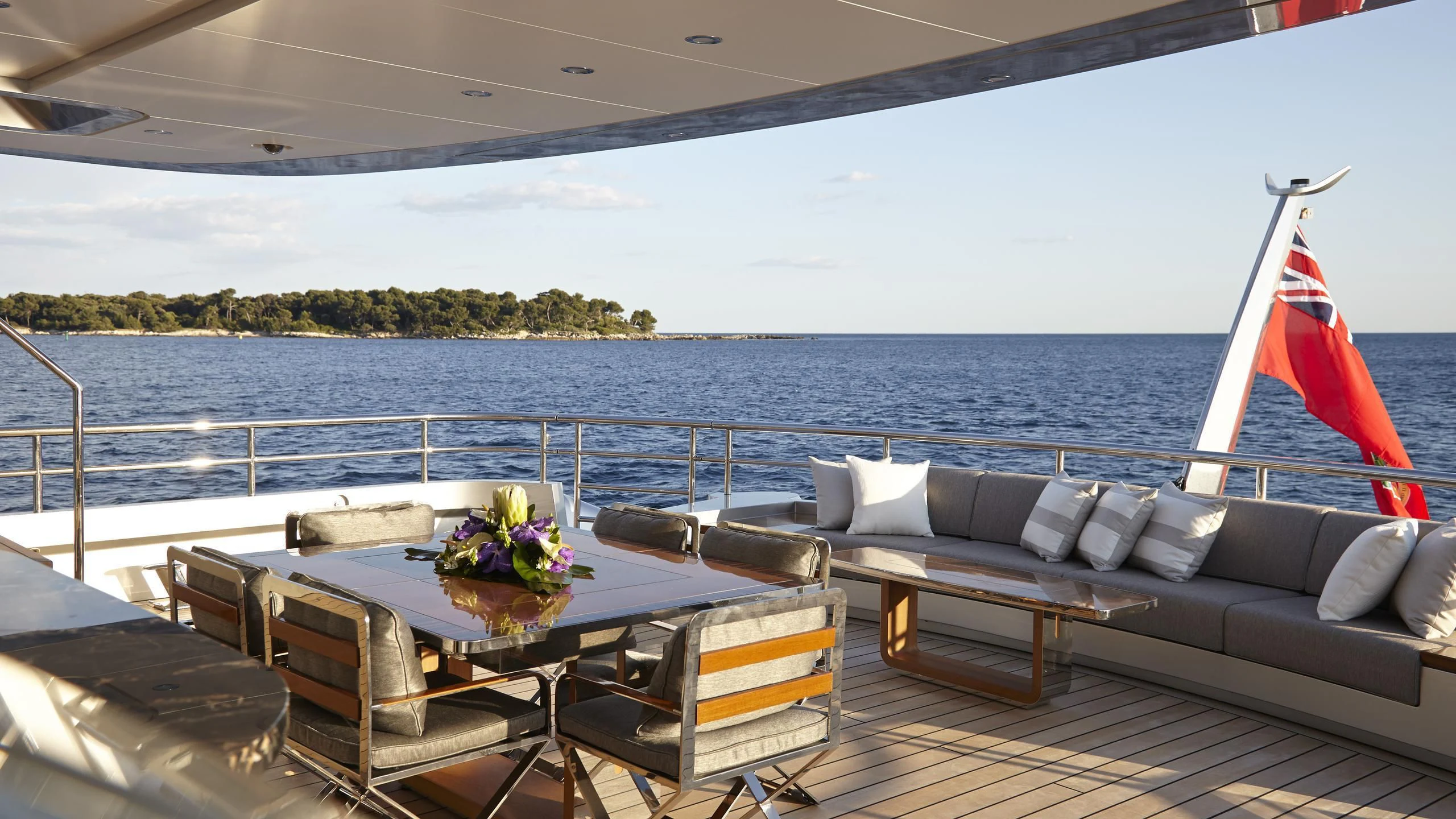 a deck with a table and chairs on it and a large body of water in the background aboard EXCELLENCE V Yacht for Sale