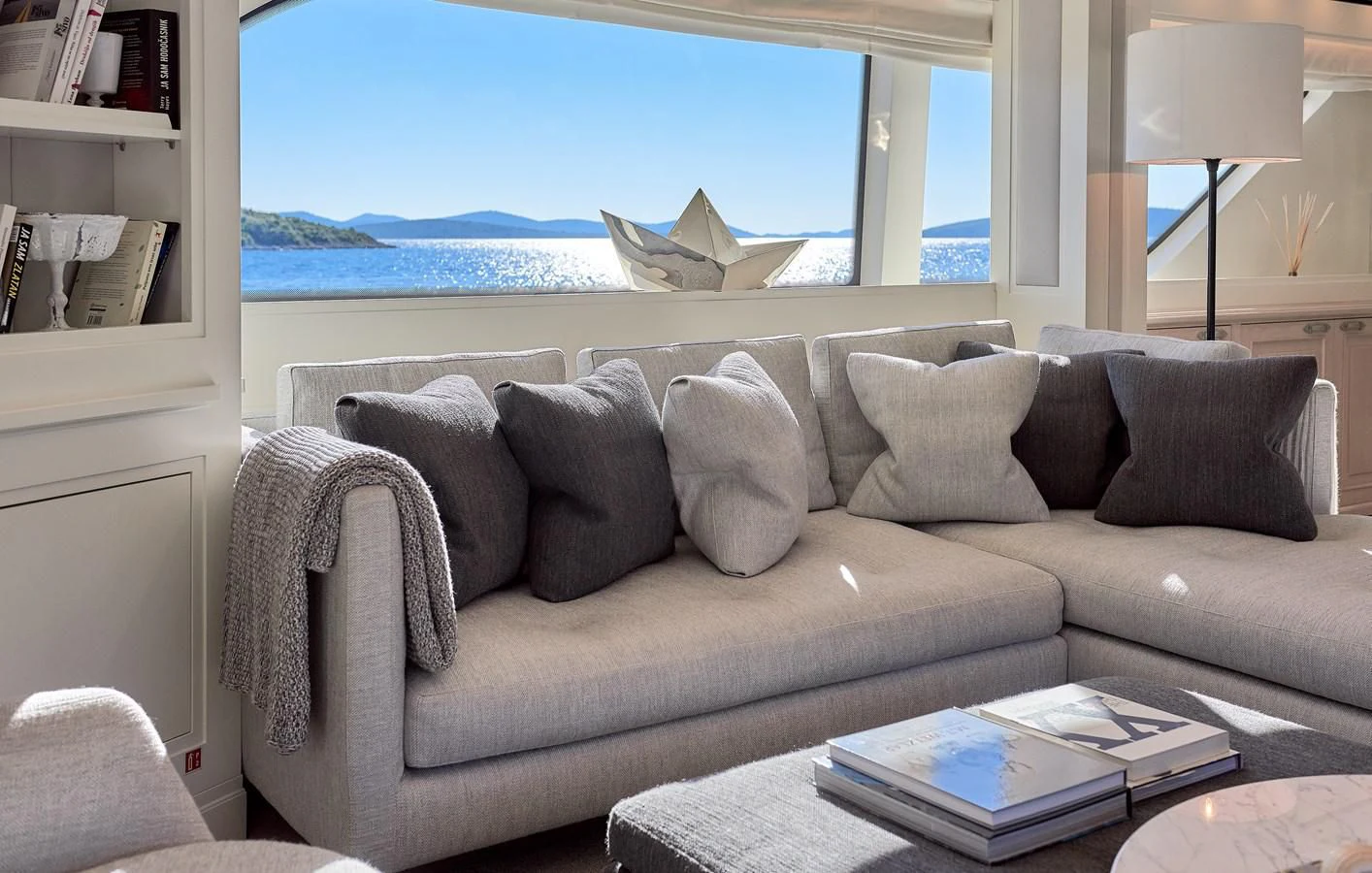 a couch with pillows and a table in front of a window aboard 2011 SANLORENZO SD92 FLYBRIDGE Yacht for Sale