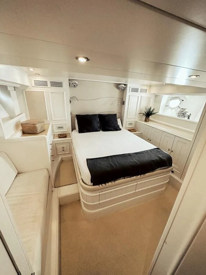 a large white bedroom with a black bed and white cabinets aboard LAZIZA Yacht for Sale