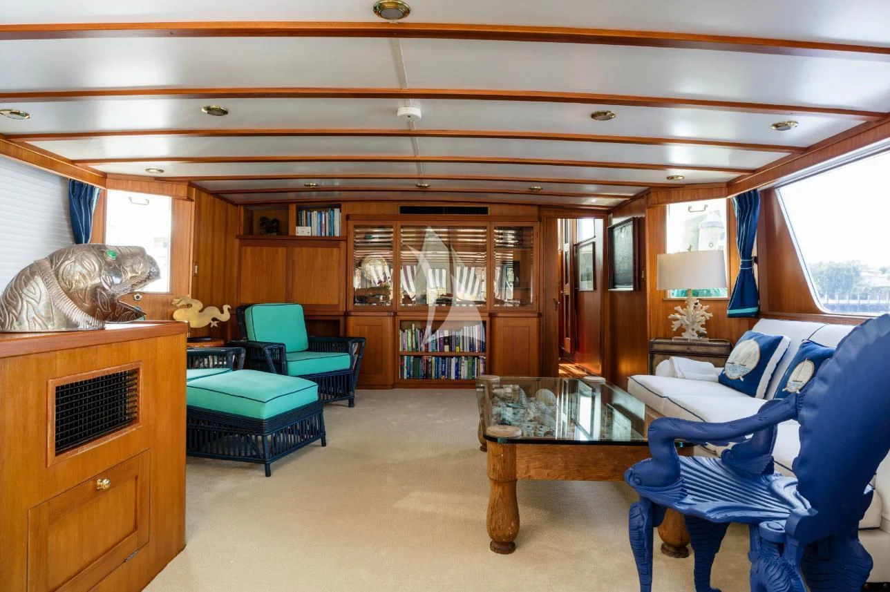 a living room with a blue chair and a table aboard SEAFARI Yacht for Sale