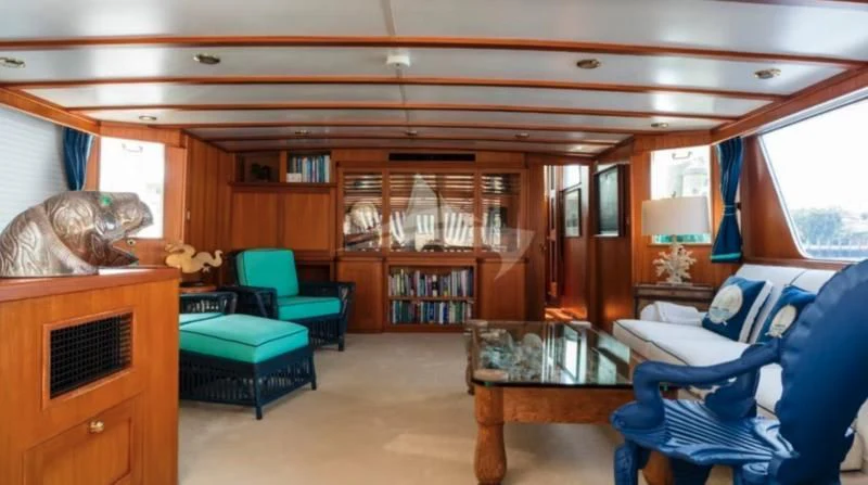 a living room with a blue chair and a table aboard SEAFARI Yacht for Sale
