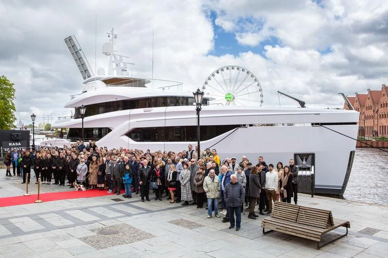 a group of people standing outside a building with a ferris wheel in the background aboard EXTRA TIME Yacht for Sale