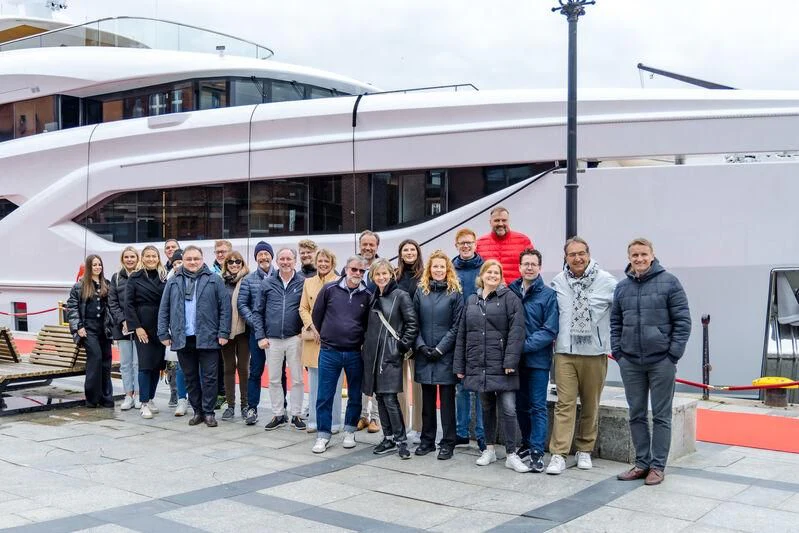 a group of people posing for a photo in front of a white bus aboard EXTRA TIME Yacht for Sale