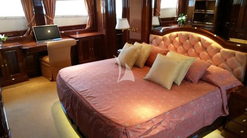 a bed with a red comforter and a laptop on it aboard SATINE Yacht for Sale
