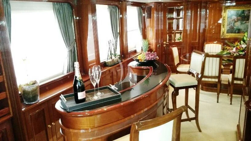 a wine bottle and glasses on a table in a room with chairs aboard SATINE Yacht for Sale