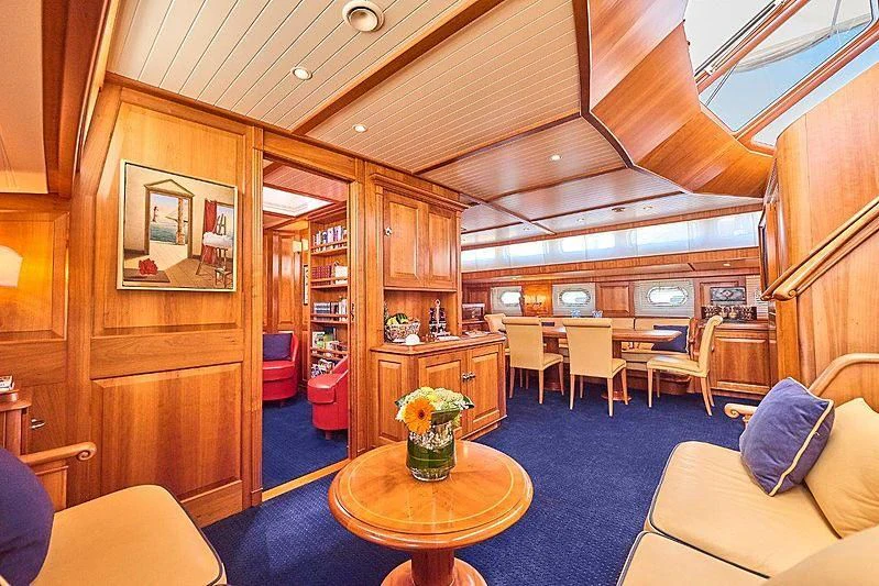 a living room with a wood paneled ceiling and a blue rug aboard ANAMCARA Yacht for Sale