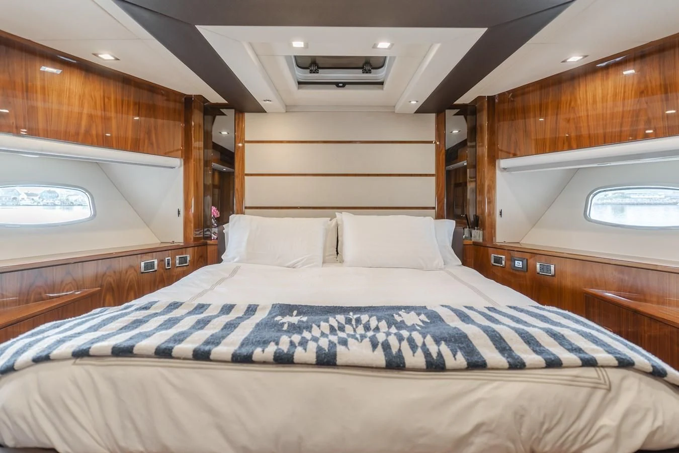 a bed with a blue and white sheet and a wooden wall aboard INDECENT PROPOSAL 4 Yacht for Sale