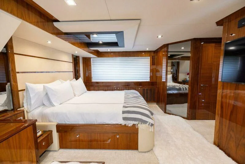 a bedroom with a bed and a mirror aboard INDECENT PROPOSAL 4 Yacht for Sale
