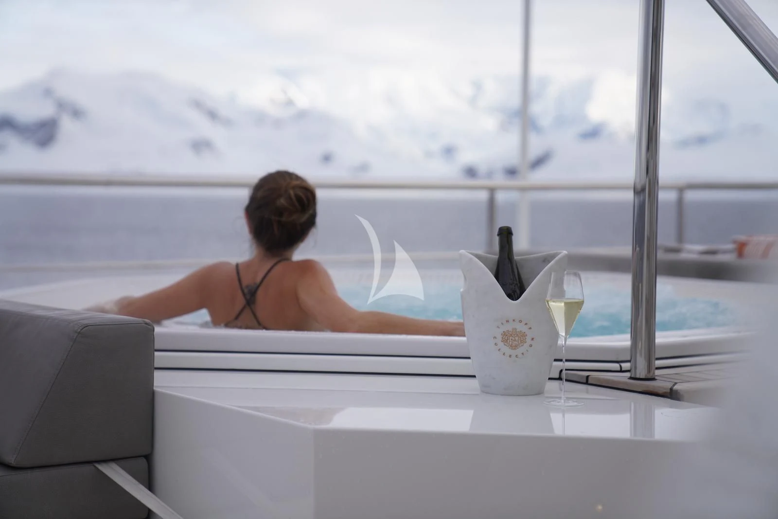 a person sitting at a table with a drink and a bottle aboard LA DATCHA Yacht for Sale