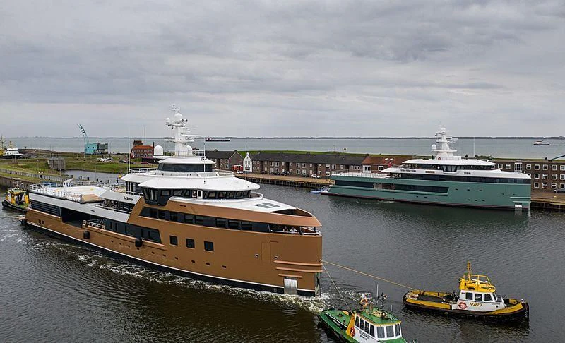 a large ship docked next to a smaller boat in the water aboard LA DATCHA Yacht for Sale
