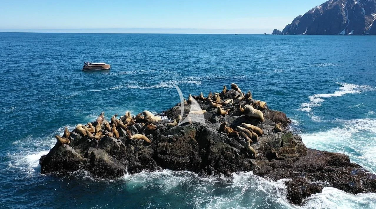 a rocky shore with a boat in the water aboard LA DATCHA Yacht for Sale