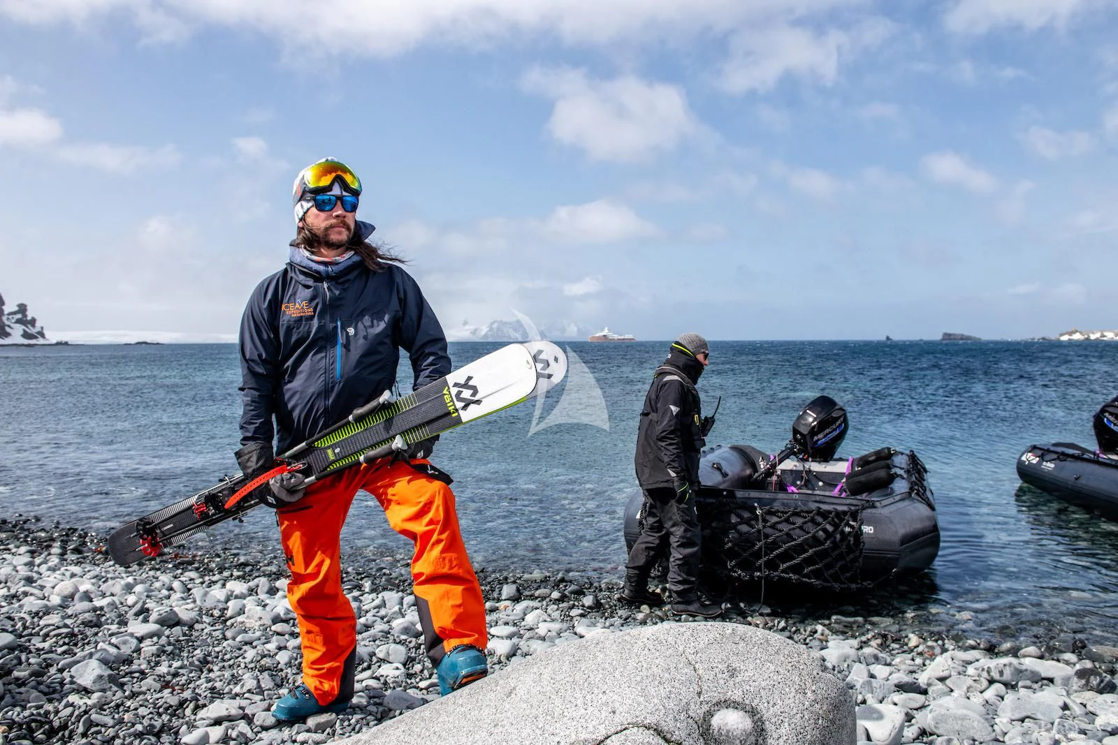 a person holding a surfboard on a rocky beach aboard LA DATCHA Yacht for Sale