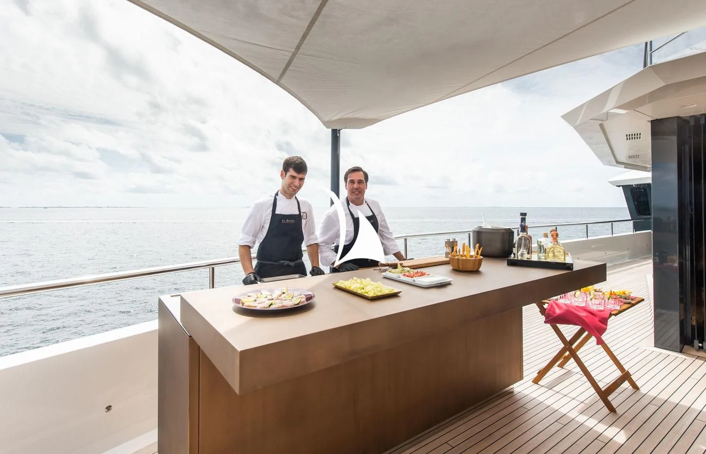 men in chef's attire standing at a table with food on it aboard LA DATCHA Yacht for Sale