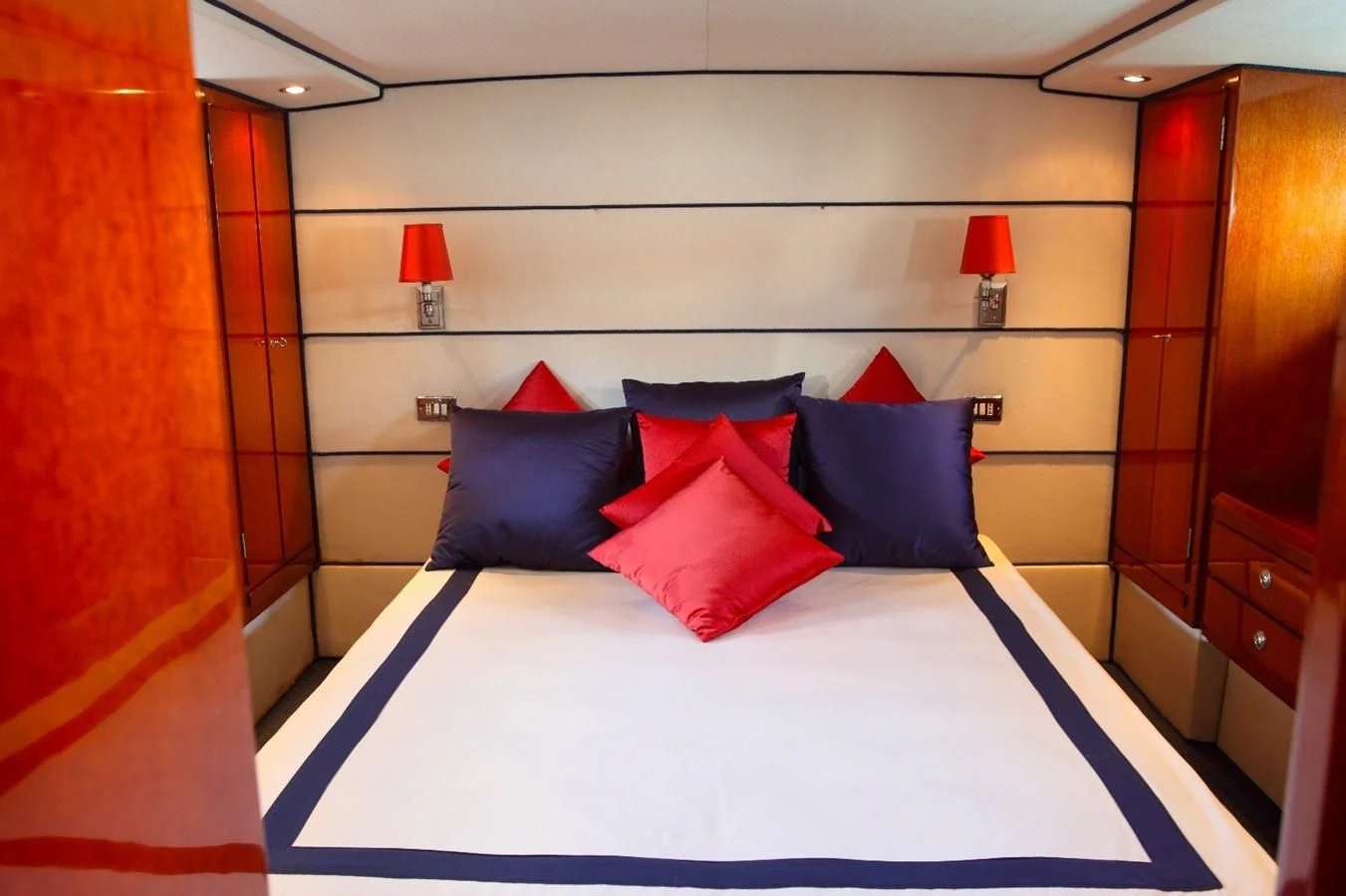 a bed with blue and red pillows aboard UNICA Yacht for Sale