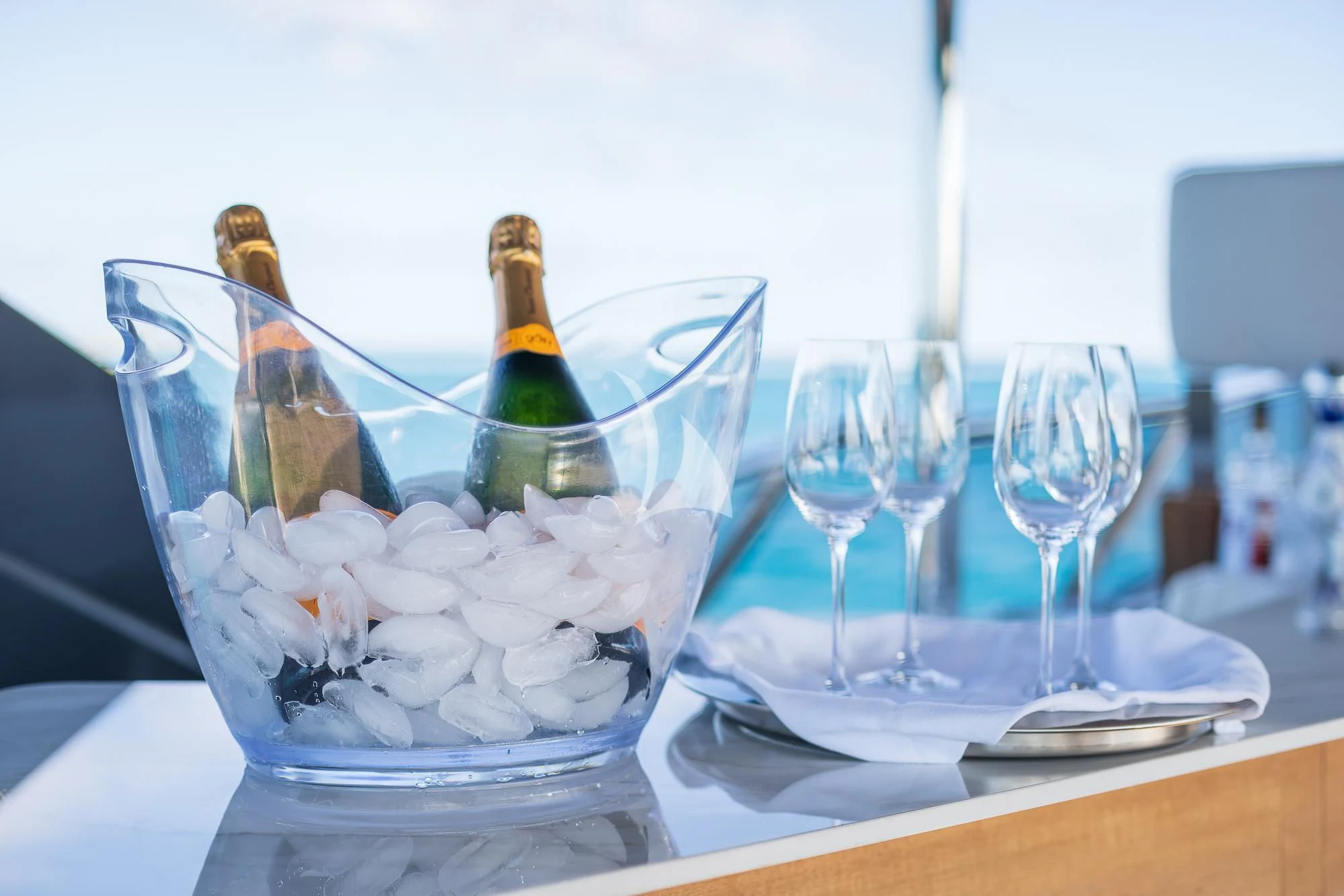 a champagne bottle and glasses on a table with a plate of food and glasses of champagne aboard SEA OWL Yacht for Sale