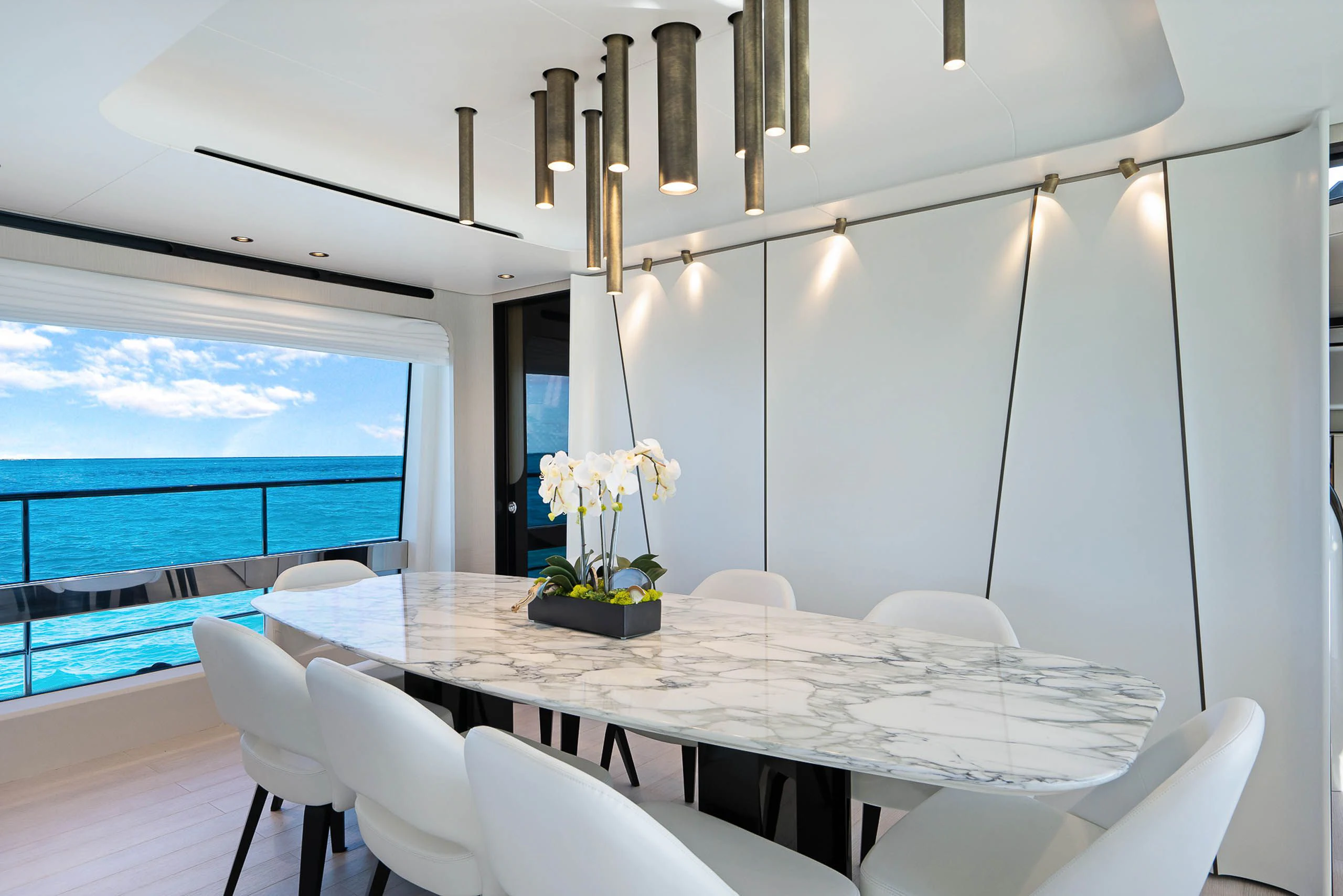 a dining table with chairs and a view of the ocean aboard SEA OWL Yacht for Sale