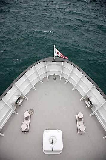a white boat with a flag on it aboard YERSIN Yacht for Charter
