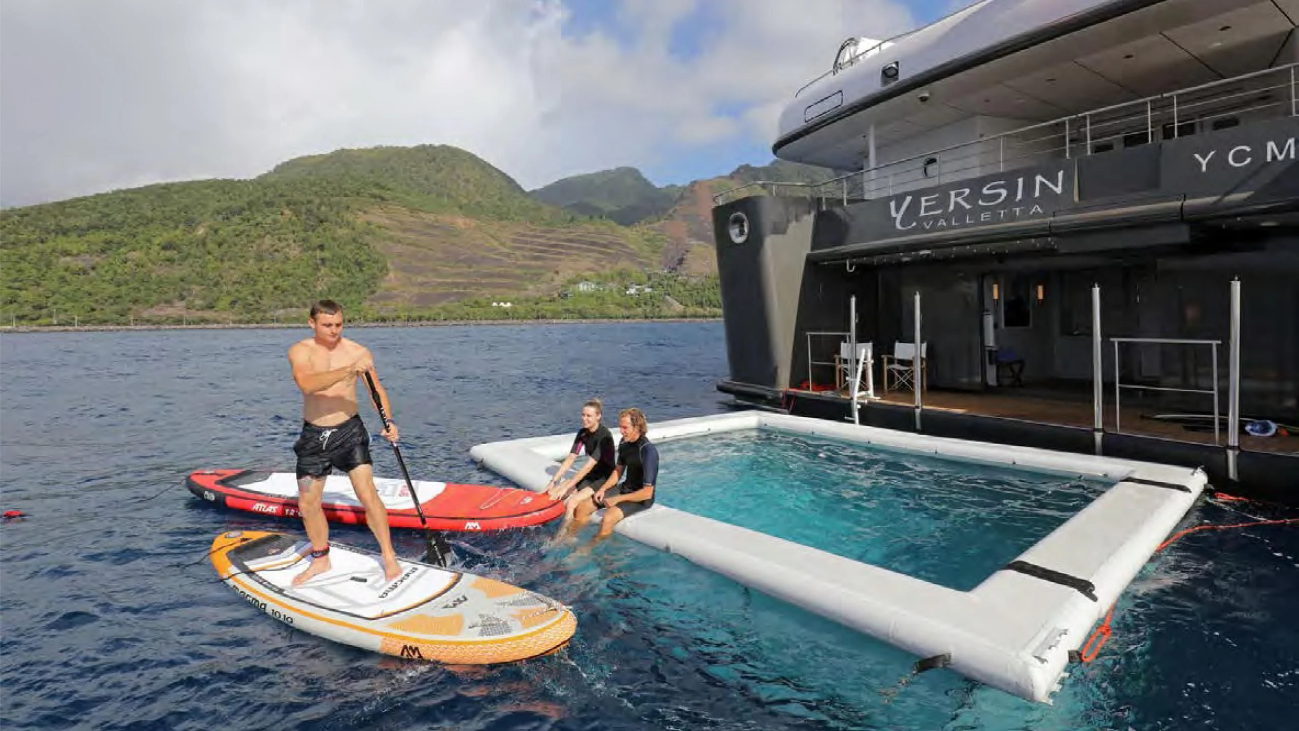 a person on a paddle board next to a boat aboard YERSIN Yacht for Charter